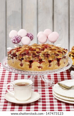 Strawberry pie on cake stand, checkered red table cloth, birthday party setting. Selective focus
