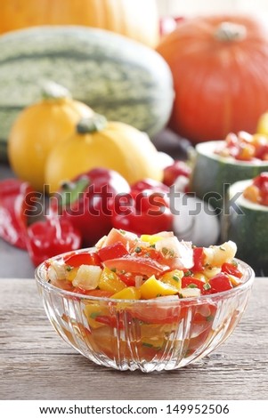 Fresh colorful vegetable salad in transparent glass bowl. Raw vegetables in the background.