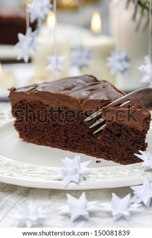 Piece of chocolate cake in white christmas table setting. Very selective and soft focus.