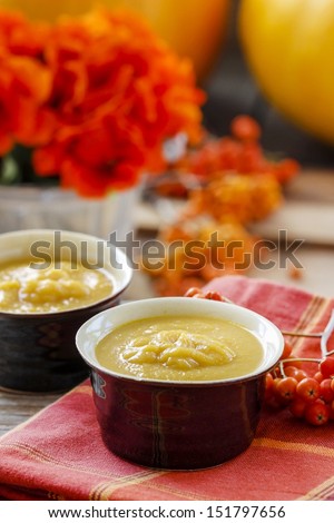 Creamy pumpkin soup on red table cloth. Rowan berry in the background. Selective focus
