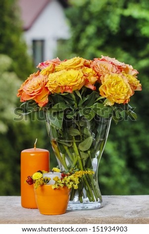 Bouquet of stunning orange roses in transparent glass vase. Garden party decor