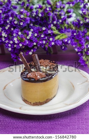 Cappuccino cake on white plate. Purple flowers in the background. Selective focus