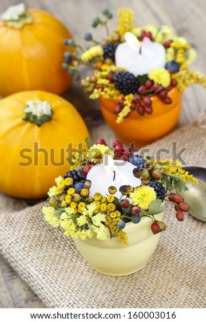 Candle holder decorated with autumn flowers and other plants. Selective focus