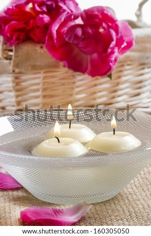 Floating candles in water among rose petals. Aromatherapy in spa