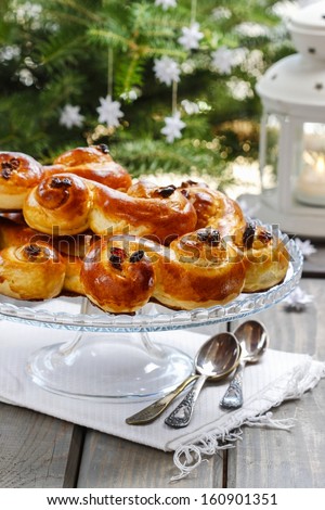 Swedish christmas. Traditional swedish buns on cake stand in christmas setting. A saffron bun, in Swedish lussebulle or lussekatt.