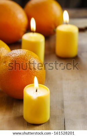 Beautiful candles and juicy oranges on wooden table. Wonderful, fresh aroma. Copy space.