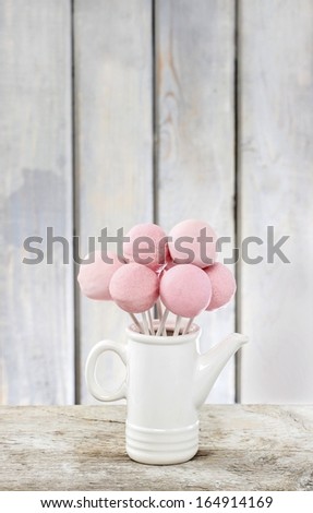 Pink cake pops on wooden table. Copy space