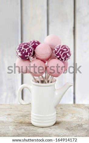 Pink cake pops on wooden table. Copy space