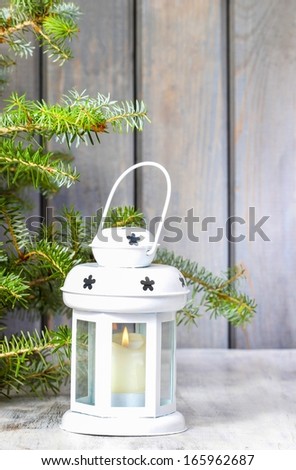 White lantern under fir branch on wooden background