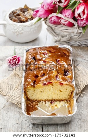 Fruit cake in rectangular pan. Bouquet of pink tulips in the background