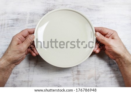 Hungry man waiting for his meal over empty plate on wooden table.