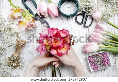 Florist at work. Woman making bouquet of spring freesia flowers