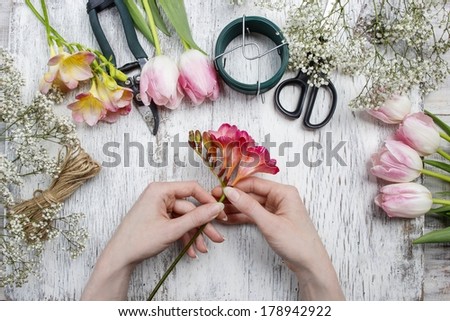 Florist at work. Woman making bouquet of spring freesia flowers