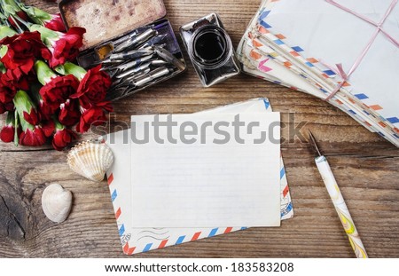 Writing a letter. Package of old letters and red carnation flowers isolated on wooden background. Copy space.