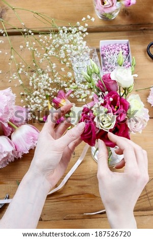 Woman making floral wedding decorations. Tiny bouquet of beautiful pink flowers