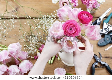 Florist at work. Woman making beautiful bouquet of pink persian buttercup flowers (ranunculus asiaticus) and pink tulips