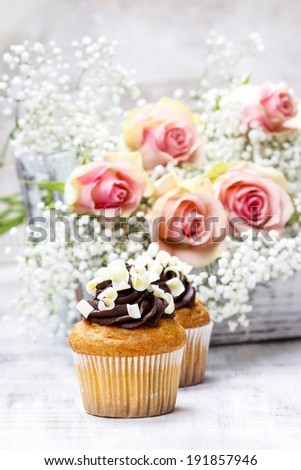 Chocolate cupcakes for wedding reception. Bouquet of pink roses in the background