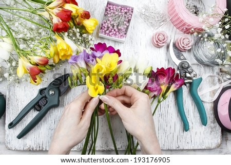 Florist at work. Woman making bouquet of freesia flowers