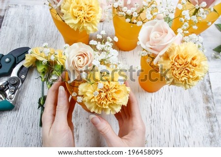 Florist at work. Woman making bouquet of pink roses and yellow carnations