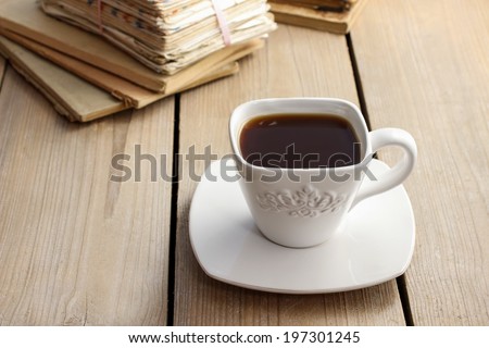 Cup of coffee on wooden table. Vintage books in the background