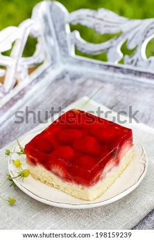 Strawberry cake with jelly topping on wooden tray in the garden