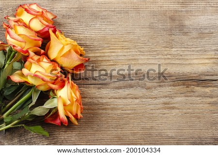Orange roses on wooden background, copy space