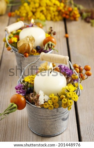 Candle holder decorated with autumn flowers and other plants. Selective focus