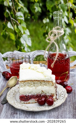 Cherry and coconut layer cake on wooden table in the garden