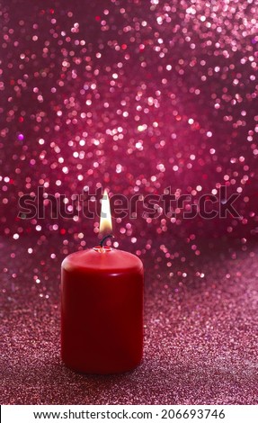 Red candle. Red glittering christmas lights. Blurred abstract background