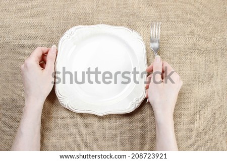 Hungry woman waiting for her meal over empty plate.