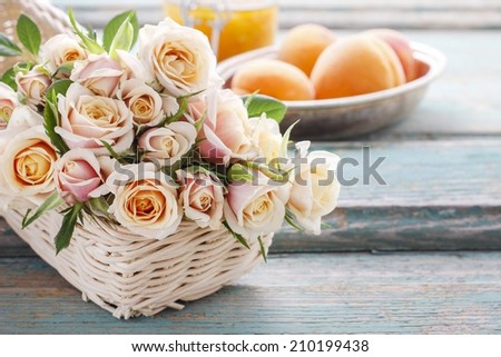 Bouquet of pink pastel roses. Bowl of peaches in the background