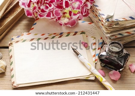 Vintage letters, ink and pen. Bouquet of pink hortensia (hydrangea) flowers in the background