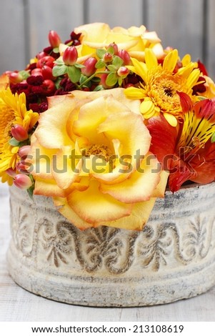 Bouquet of orange roses and autumn plants in vintage ceramic vase
