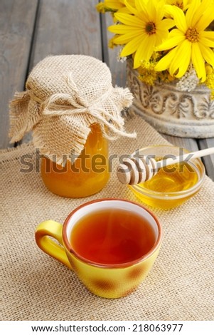 Cup of tea and jar of honey on wooden table