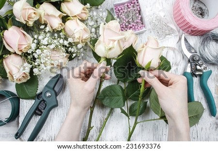 Florist at work. Woman making bouquet of pink roses.
