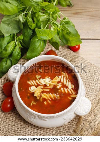 Bowl of tomato soup and basil plant in the background