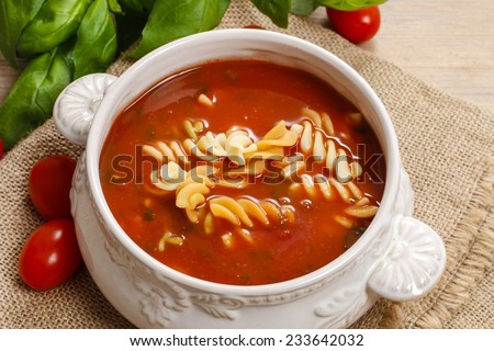 Bowl of tomato soup and basil plant in the background