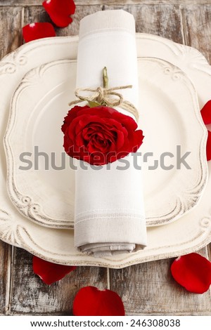 Romantic dinner: napkin ring made with red rose, petals around the plate