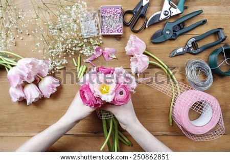 Florist at work. Woman making beautiful bouquet of pink persian buttercup flowers (ranunculus asiaticus) and pink tulips