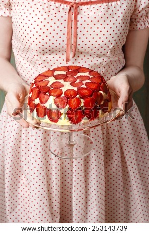 Woman holding strawberry cake on cake stand