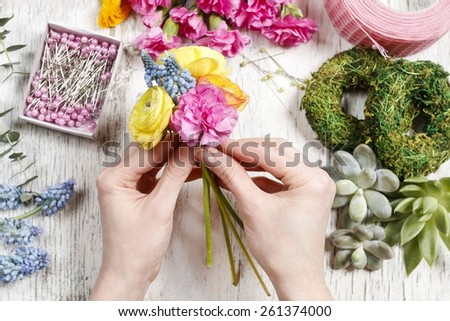 Florist at work. Woman making bouquet of ranunculus, muscari and carnation flowers