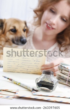 Ink stand. vintage pen and letters. Woman reading letter to a lovely puppy.