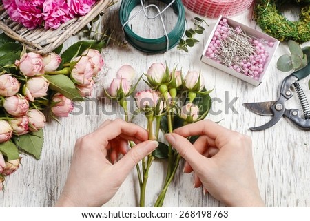 Woman making bouquet of pink roses. Florist at work.