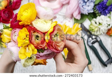 Florist at work. Woman making bouquet of persian buttercup flowers (ranunculus) and freesia flowers