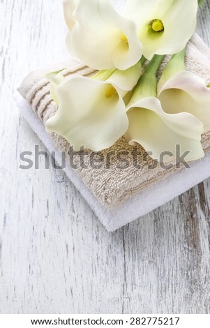 Towels and bouquet of white calla flowers on white rustic wooden table