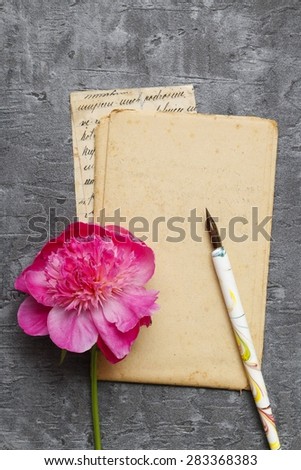 Handwritten letters and pink peonies on grey background, copy space