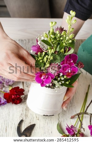 Florist at work. Woman making floral arrangement with orchid flowers and gypsophila paniculata, copy space