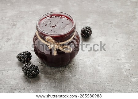 Jar of blackberry jam on stone background, copy space