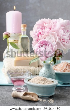 Spa set: sea salt, bars of handmade soap, scented candles, towels and bouquet of peonies.