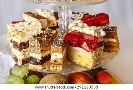 Assorted cakes, cookies and fruits on glass cake stand